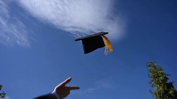 一个女人的手向天空扔毕业帽的特写