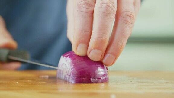 男人的手在切菜板上用尖刀切洋葱