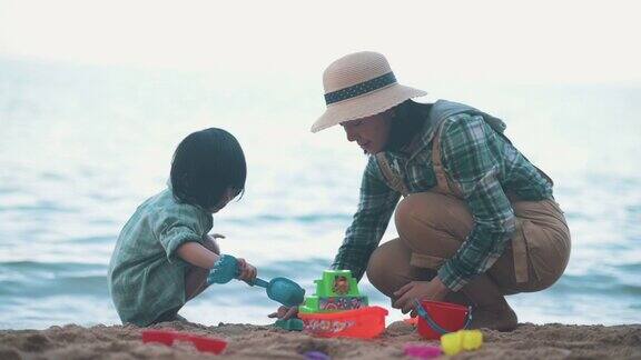亚洲妈妈和儿子在海滩上玩玩具