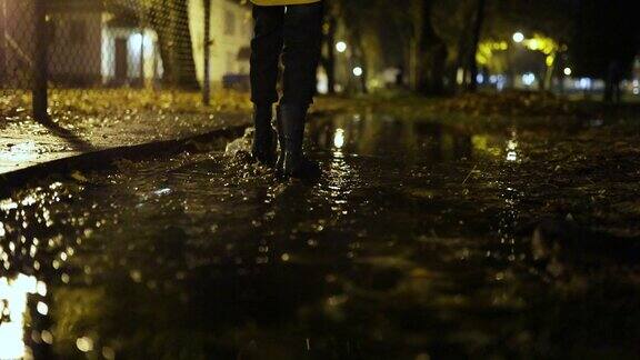 小男孩在秋天的夜晚走在水坑里