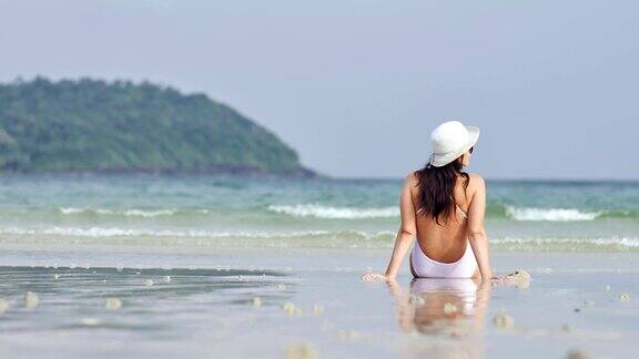 穿着白色泳衣的年轻女子在热带海滩上放松