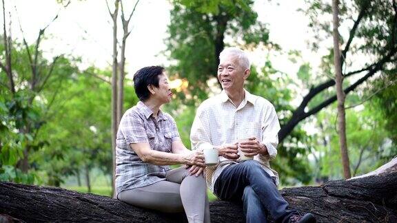 快乐的老亚洲老夫妇在公园约会早上咖啡的谈话