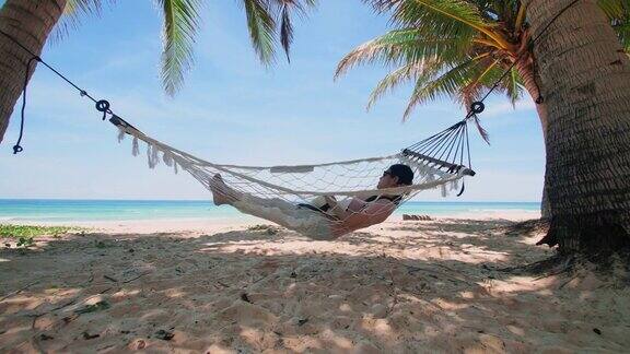 泰国普吉岛亚洲年轻女子放松与书的吊床在日落的海滩年轻漂亮的女人在吊床上荡秋千夏天假日