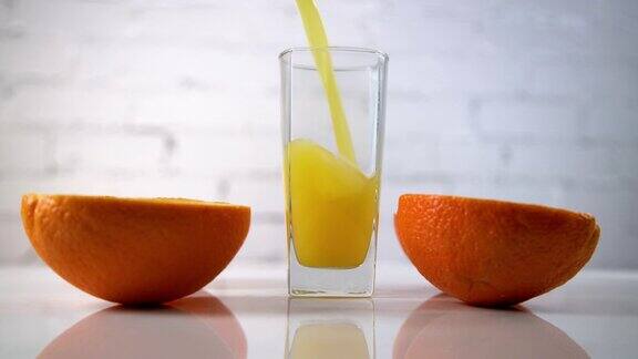 鲜榨的橙汁倒进桌子上的玻璃杯里旁边放着几片橙子清爽的黄色饮料与水果在白色的背景