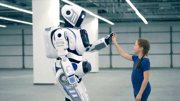 一个小女孩和一个人形机器人击掌