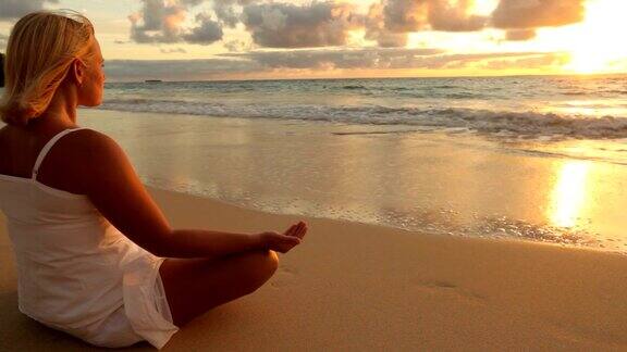 日出时在海滩上做瑜伽的女人
