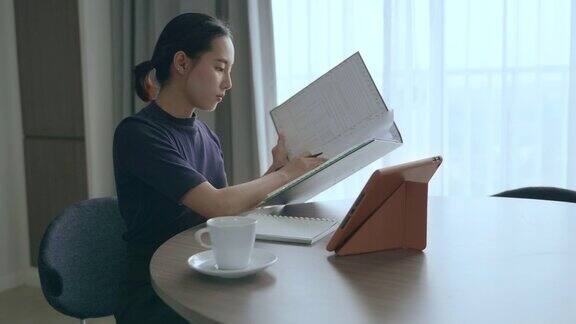 亚洲女性在家里用平板电脑工作的场景
