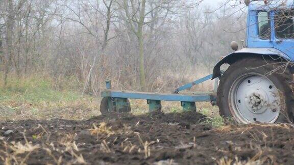 深秋蓝色的拖拉机在田间犁沟