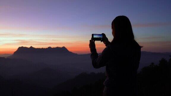 女旅行者在日出的时候在山上拍摄一个美妙的地方