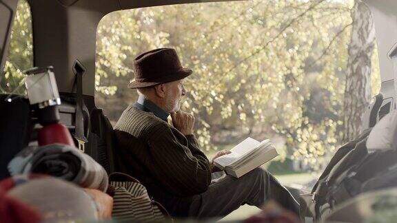 老男人坐在车后面看书