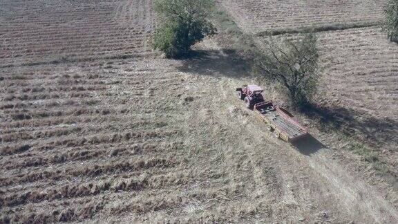 跟在拖拉机后面拖着一辆拖车在干燥的土地上行驶