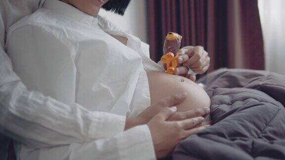 一对亚洲怀孕夫妇躺在床上拥抱
