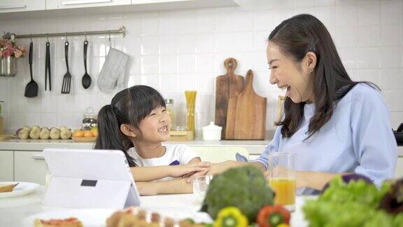 4k年轻的亚洲母亲和女儿快乐和乐趣准备蔬菜和水果沙拉在一个现代化的白色厨房女儿做饭时心情愉快