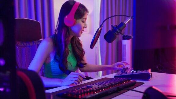 亚洲有吸引力的音频DJ女性对着麦克风说话广播年轻美丽的女博主影响戴耳机和记录早上的新闻播客节目在家里的播音室