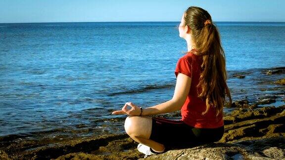 年轻女孩在海边做瑜伽冥想