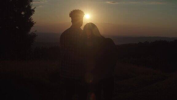 夕阳西下多民族情侣在山顶拥抱的浪漫剪影