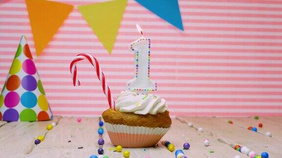 祝1岁的宝宝生日快乐美丽的快乐生日视频背景1岁在粉红色的背景与奶油纸杯蛋糕和蜡烛与火