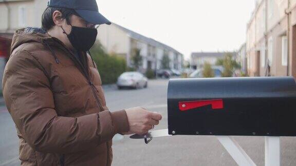 一名戴着可重复使用的保护面罩的男子将装有选票的信件放入住所附近的邮筒