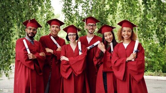 这是一组毕业生的照片他们手拿毕业证书双手交叉站在户外穿着学士服和学位帽微笑着看着镜头