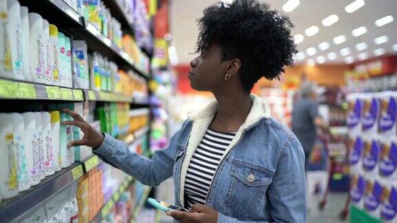 年轻女子在超市边走边用手机
