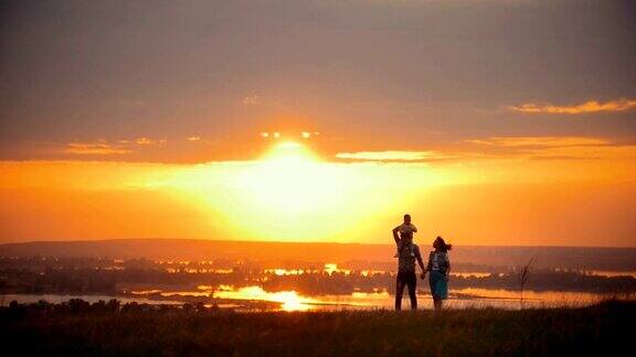 一家人在夏日的夕阳下散步爸爸妈妈手牵着手儿子坐在他的肩膀上
