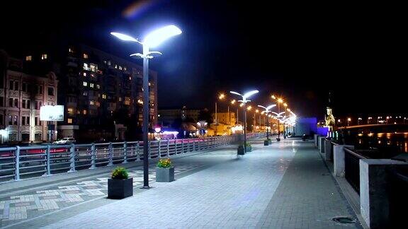 夜晚的城市码头人们行走汽车行驶路灯亮着