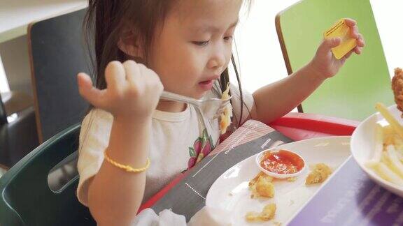 小女孩吃着炸薯条和炸鸡