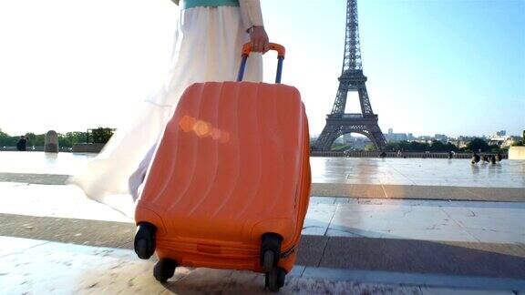 拿着橙色手提箱的女人去巴黎旅行