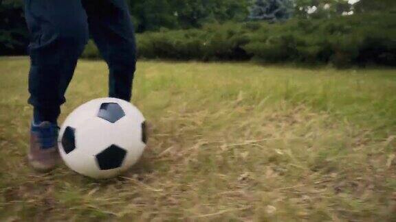 在室外踢足球的孩子那个男孩在公园里踢足球把脚放在球上