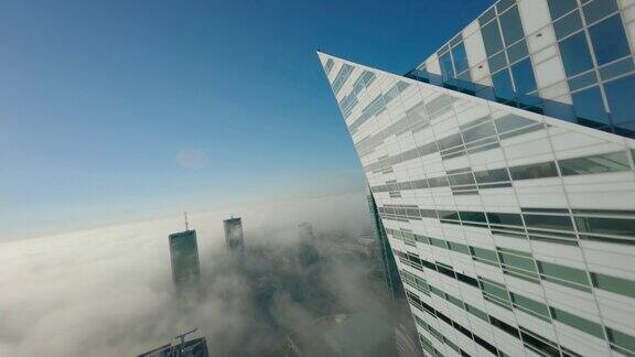 第一人称无人机飞行观看阳光明媚的现代城市景观在白天与高大的玻璃摩天大楼在云