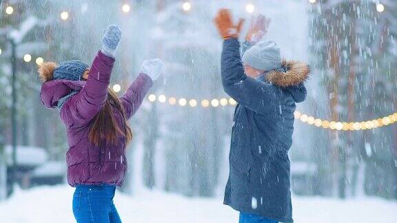 一对穿着夹克和帽子的有趣夫妇在冬天的公园里扔雪