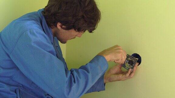 年轻的专业电工做插座修理的中镜头