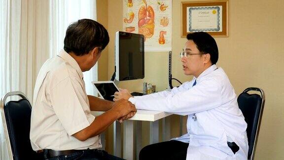 亚洲男医生使用数字平板电脑与资深病人在病房讨论