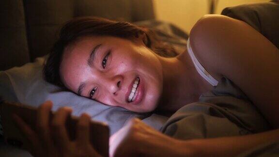 一个亚洲女人在床上玩手机