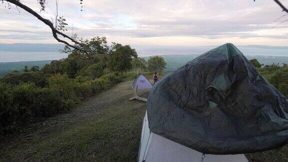 风景如画的山上游客夫妇在绿色的草地上搭起帐篷