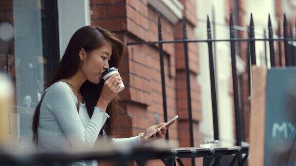 年轻的中国女子在咖啡馆使用智能手机(慢镜头)