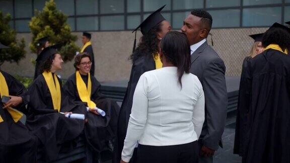 毕业典礼结束后一位美丽的黑人女子和她的同学交谈然后和她的父母打招呼她非常兴奋