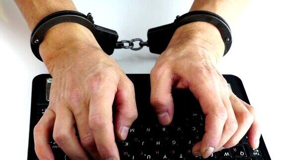 男性手戴手铐在笔记本电脑上打字预防犯罪黑客攻击信息技术惩罚数字犯罪数据安全保存软件