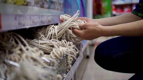 一位年轻女子在超市挑选并购买了一根绳子