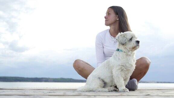 年轻女子与她的狗在海岸线上放松