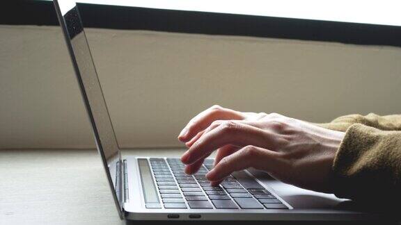一位女士在办公室的木桌上用手触摸笔记本电脑商人在笔记本电脑键盘和触控板上打字现代工作空间概念