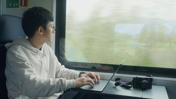 亚洲商人在移动的火车上用笔记本电脑工作