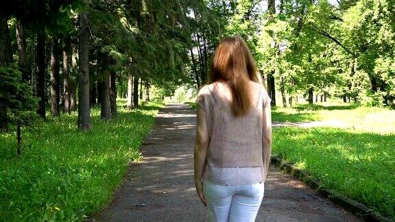 年轻的白人迷人的微笑女人在公园散步
