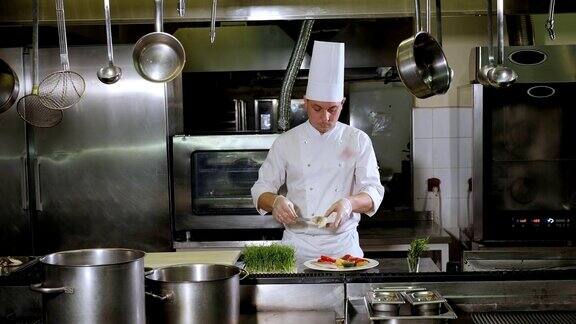在餐厅的厨房里厨师把烤好的剑鱼和蔬菜放在盘子里