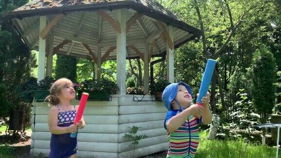 可爱的快乐的孩子学龄前的小女孩和男孩的孩子玩有乐趣的水泵枪在外面阳光明媚公园里的一天儿童后院花园游戏夏天运动假期家庭童年