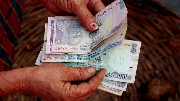 贫困可怜的女人在数印度卢比钞票特写
