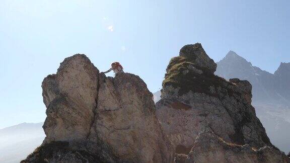 女性登山运动员登上顶峰或岩石的顶峰