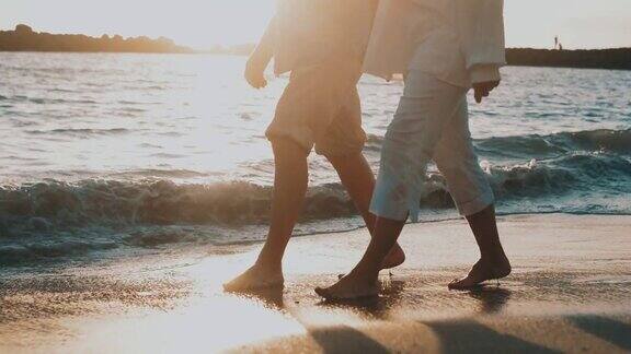 黄昏下两个人手牵手一起在沙滩上散步