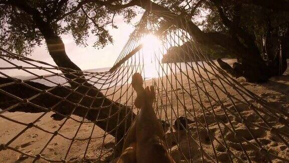 靠近亚洲女人的脚休息和睡觉在沙滩上的吊床在暑假