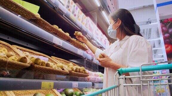 新常态保持社交距离亚洲女性戴着防护口罩在超市选购水果新冠肺炎疫情爆发后女性在超市买水果